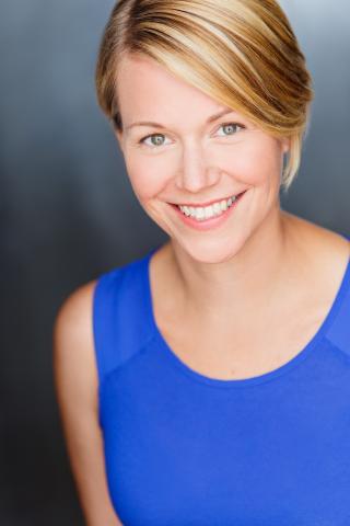 Young blonde woman in a blue sleeveless top smiling at the camera